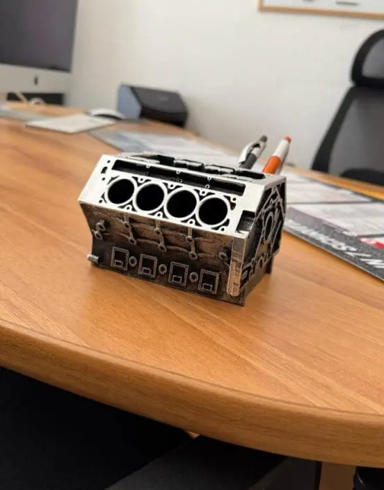 fahrschule-haidhausen-muenchen-leuchtenberg-empfangsbereich-schreibtisch Detailaufnahme eines Schreibtischs im Empfangsbereich der Fahrschule Leuchtenberg in Haidhausen – mit originellem Motorblock-Stiftehalter und moderner Büroausstattung.