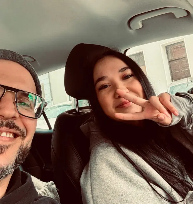 fahrschule-muenchen-preise Schülerin zeigt Peace-Zeichen nach bestandener Fahrstunde – authentischer Einblick in die Atmosphäre und Preise der Fahrschule Leuchtenberg in München.