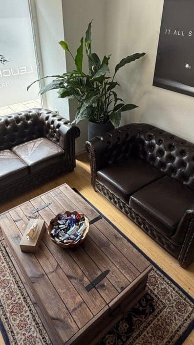 Empfangs- und Wartebereich der Fahrschule Leuchtenberg in Haidhausen München – stilvolle Chesterfield-Sofas, Holztisch und entspannte Atmosphäre für Fahrschüler:innen.