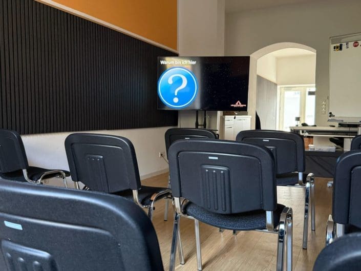 Moderner Theorieraum der Fahrschule Leuchtenberg in München – mit Stuhlreihen, Whiteboard und großem Bildschirm für interaktiven Unterricht. Raum für den theoretischen Unterricht.